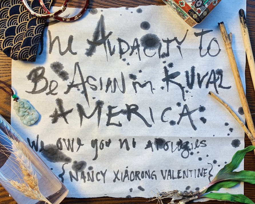 A photo of a painted cloth that reads The Audacity to Be Asian in Rural America, Nancy Xiaorong Valentine